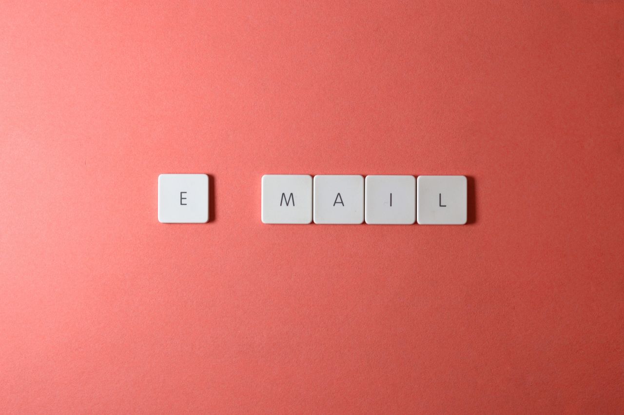 creative-03 Flat lay of keyboard letter tiles spelling email on coral backdrop.