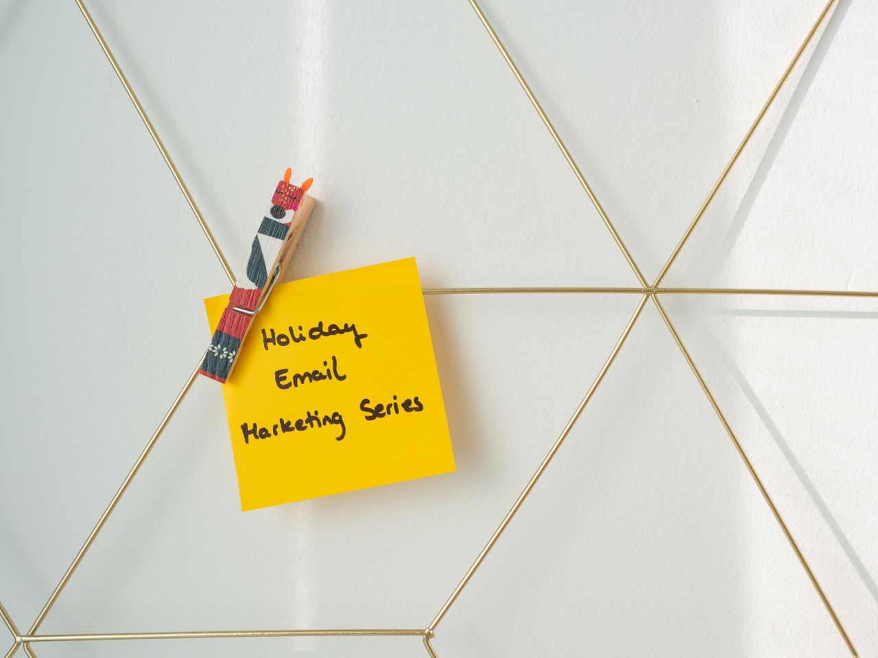 brand-02 Bright yellow sticky note with holiday email marketing message clipped to a wireframe wall.